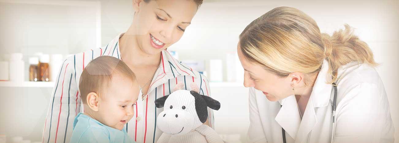 Bebé acompañado por su mamá, siendo revisado en consulta por pediatra