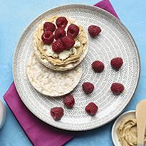 Tostadita de arroz con crema de maní, queso crema y frambuesas.